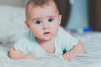 Baby in Whit Shirt Crawling on Bed