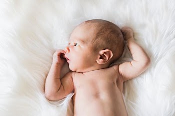 baby lying on white fur surface
