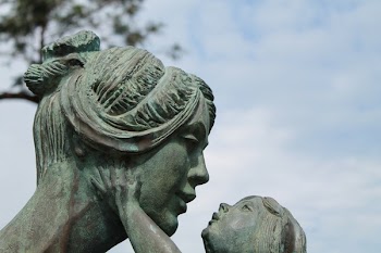 Baby Touching Face of Mother Statue during Day Time
