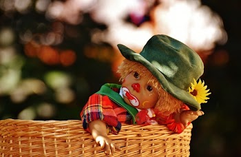 Baby Wearing Green Hat and Red Black and Yellow Plaid Top Inside Brown Wicker Basket