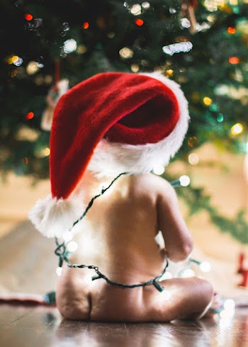 Baby Wearing Red Santa Hat Sitting Near Christmas Tree