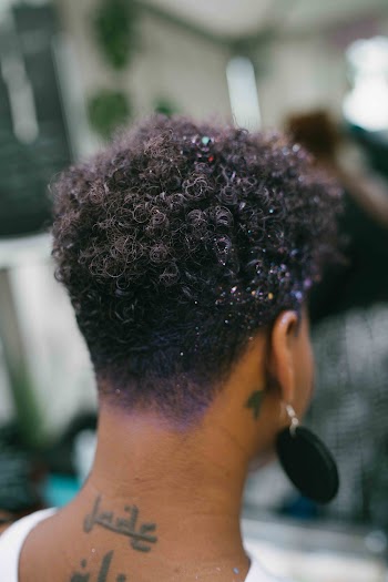 Back View of a person with curly hair and tattoos on the neck
