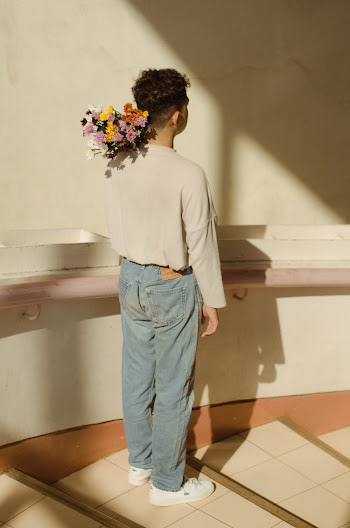 Back View Of A Young Man Carrying A Bouquet Of Flowers on His Shoulder