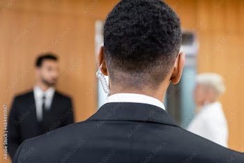 back view of african american security man near blurred senior woman with bodyguard on blurred background.