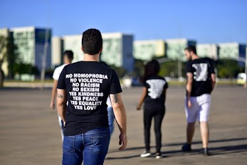 Back view photo of a man wearing a black printed t-shirt and blue denim jeans
