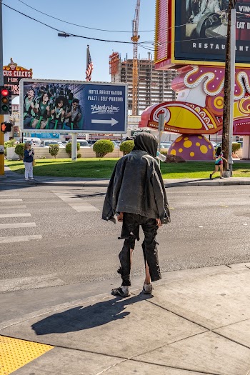 Back view photo of a person wearing grey jacket standing on the sidewalk