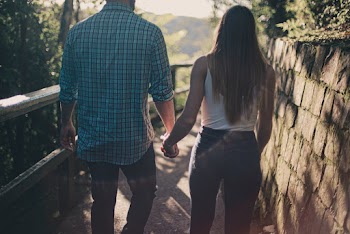 Back View Photo of Couple Holding Hands While Walking Along Pathway