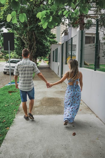 Back View Photo of Couple Holding Hands While Walking on Sidewalk