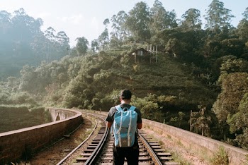 Back View Photo of Man Standing in the Middle of a Train Track