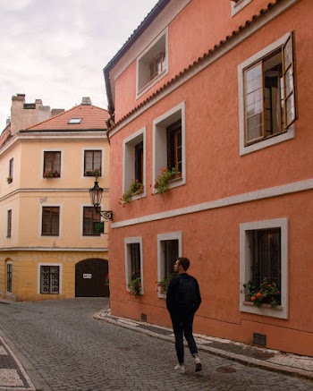 Back View Photo of Man Walking Near Concrete Buildings