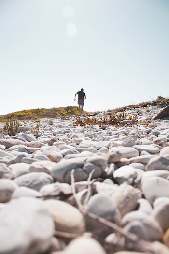 Back view Photo of Person Walking on Rocky Field
