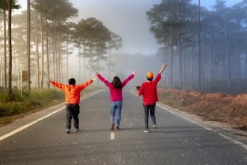 Back view photo of three people walking on road