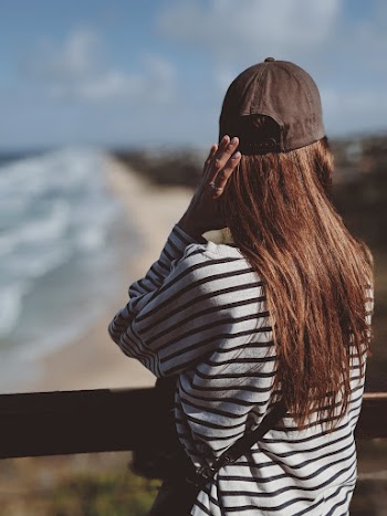 Back View Photo of Woman in Black and White Striped Long-sleeved T-shirt and Black Cap Looking into the Distance