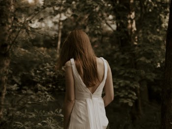 Back View Photo of Woman in White Dress Walking in the Woods
