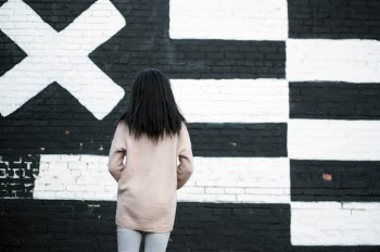 Back View Photo of Woman Standing in Front of White and Black Painted Wall