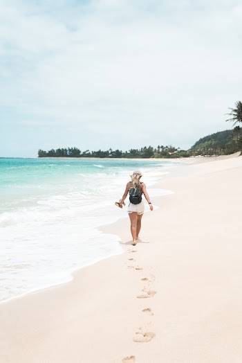 Back View Photo of Woman Walking Alone on the Beach