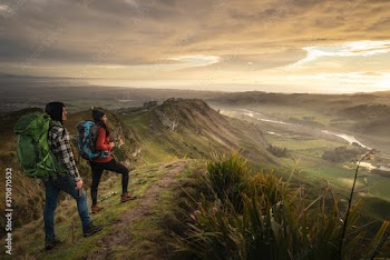 Backpacker couple standing at the peak of a mountain looking at the horizon