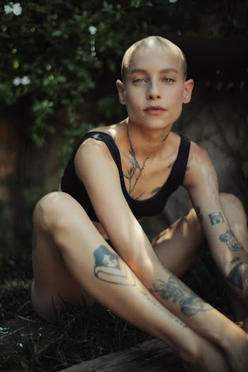 Bald Woman Wearing Black Crop Top Sitting on Grass