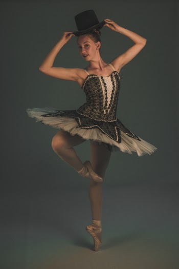 Ballerina in Dance Form Holding Her Black Hat