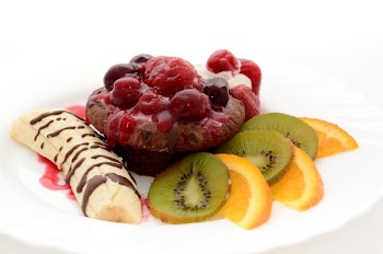 Banana Drizzled With Chocolate Syrup Beside Chocolate Cupcake With Raspberry and Kiwi and Orange Slices on the Side on White Plate