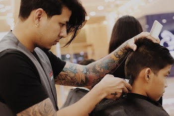 Barber Using Hair Trimmer On Boy's Hair