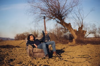 Bass player posing outdoor in an old chair