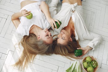 Beautiful and sporty women in a kitchen with vegetables Free Photo