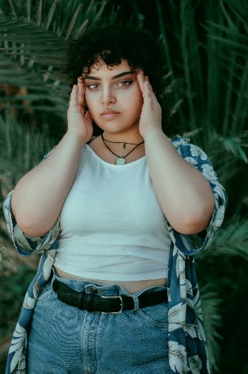 Beautiful capture of an oversized pretty girl in front of a palm tree .
