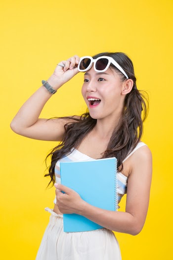 Beautiful female students hold notebooks and pens Free Photo