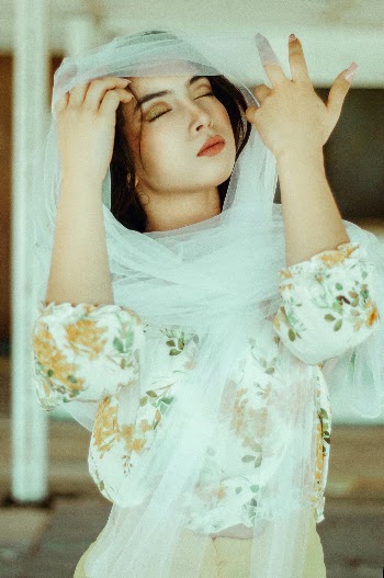 Beautiful fine art portrait of a gorgeous model wearing a long scarf and closing her eyes.