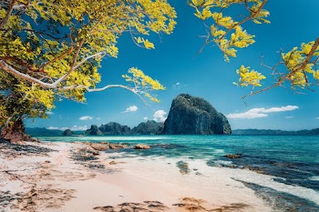 Beautiful landscape scenery of El Nido coastline. Unique amazing Pinagbuyutan island in background framed by tree branches. Palawan, Philippines Free Photo