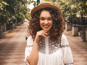 Beautiful smiling model with afro curls hairstyle dressed in summer hipster white dress. Free Photo