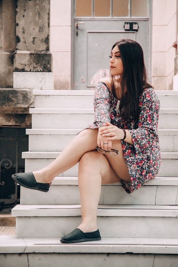 Beautiful woman in a floral dress on white stairs