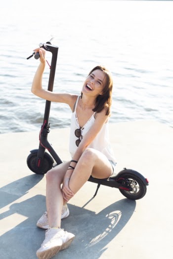 Beautiful woman smiling while sitting on scooter Free Photo