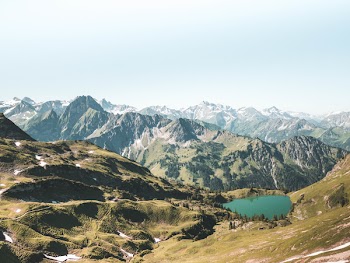 Beige and Green Mountain With Teal Lake Under White Sky at Daytime