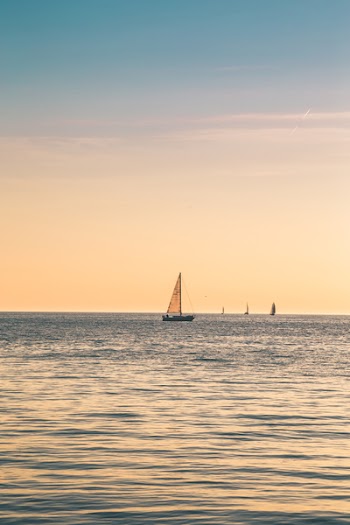 Beige Sailboat Under Clear Skies