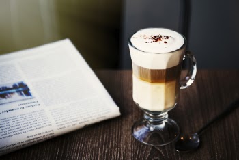 Beverage in Clear Glass Mug Near Newspaper on Table
