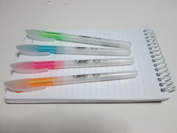 Bic Orange and White Ball Point Pens on Top of Lined Paper Notebook
