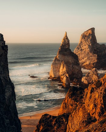 Big Rock Formations Near Body of Water Under Blue and White Sky