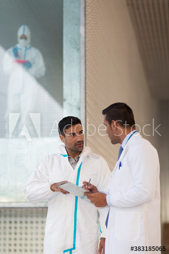Biochemists in clean suits using digital tablet