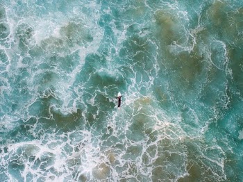 bird's-eye view photo of man surfing on body of water