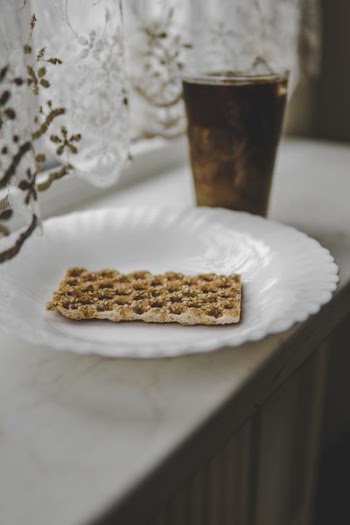biscuit on round white ceramic plate near full drinking cup with brown liquid