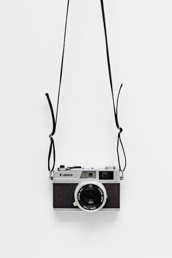 black and gray Canon camera on white surface