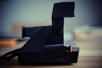 Black and Gray Instant Camera on Brown Wooden Table