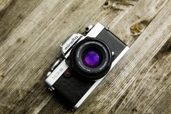 Black and Gray Minolta Dslr Camera on Top of Brown Wooden Surface
