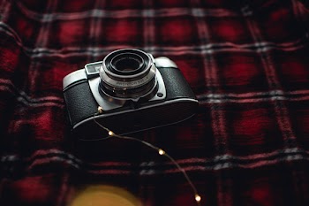 Black and Gray Point-and-shoot Camera on Red, Black, and White Plaid Textile