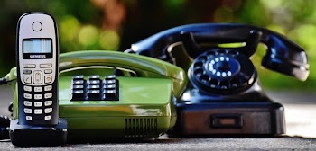 Black and Green Rotary Telephones Beside Cordless Home Telephone