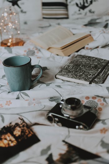 Black and Silver Bridge Camera Near Green Ceramic Mug, Open Book, and Gray and Black Hardbound Books