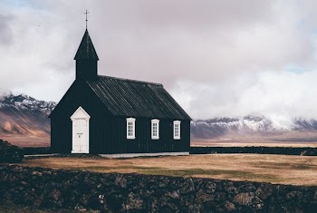 black and white church near open field background of mountain view