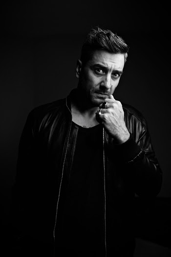 Black And White Photo Of A Man Wearing A Leather Jacket Clenching His Fist